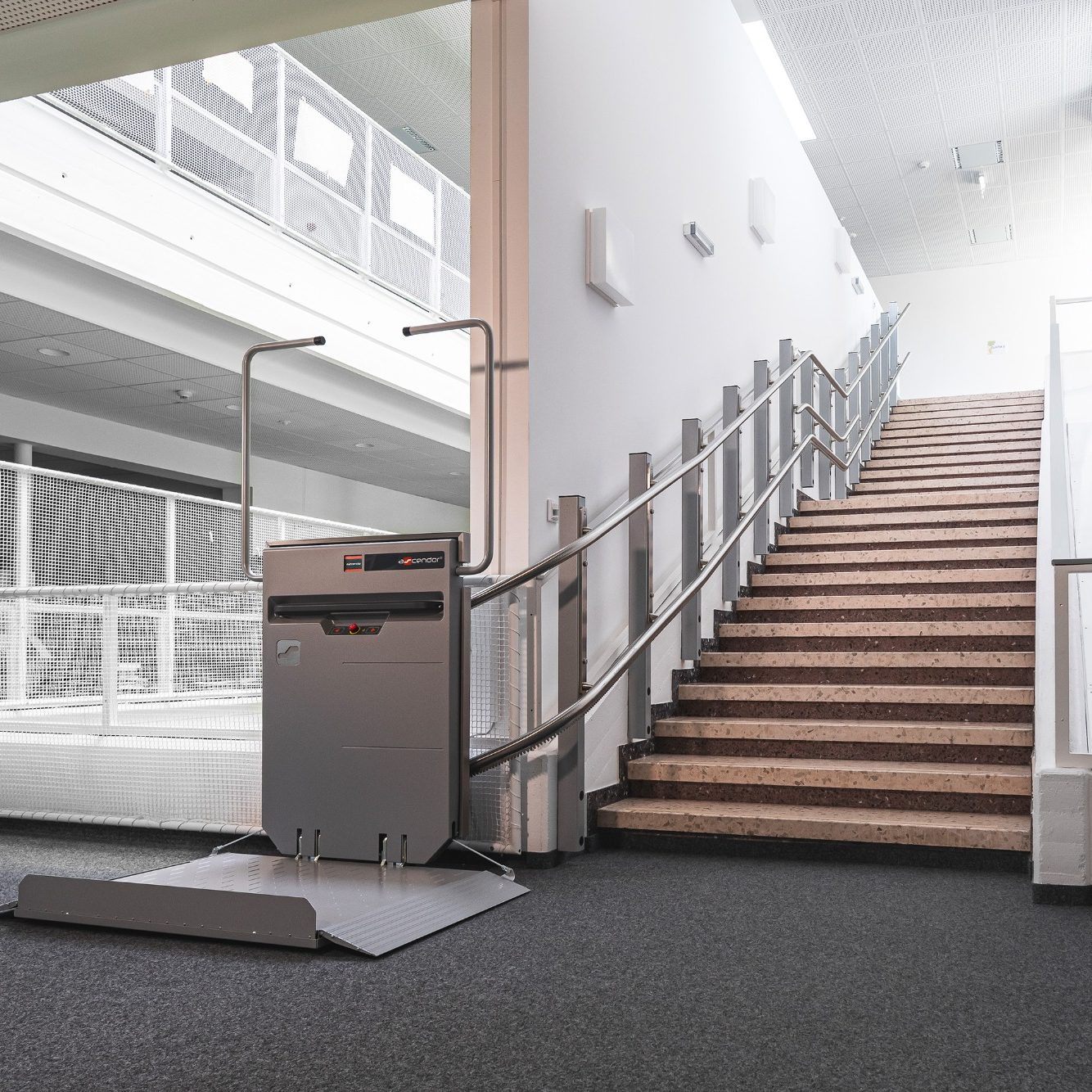Treppenlift neben einer Treppe in einem modernen Gebäude in Herford. Treppenlift neben einer Treppe in einem modernen Gebäude.